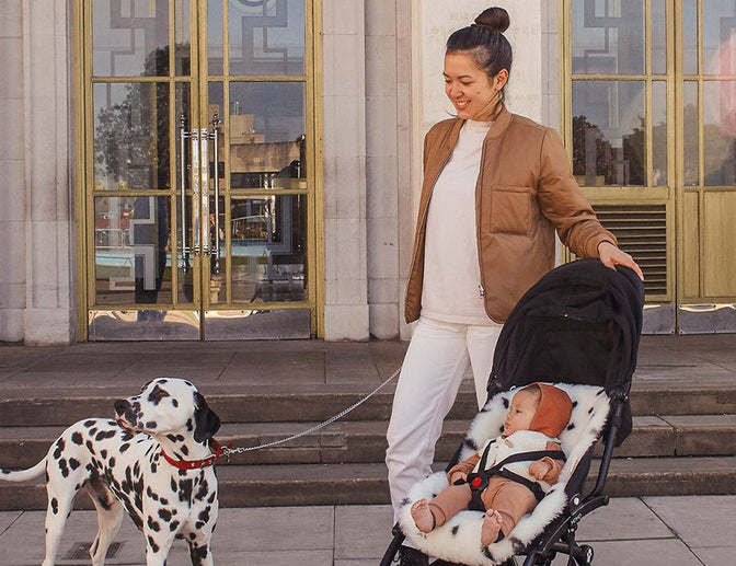 Matka z dzieckiem i psem na wiosennym spacerze. Jak ubierać niemowlę wiosną?
